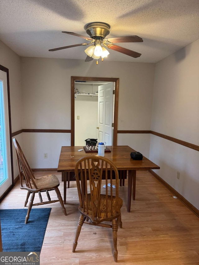 dining room featuring a textured ceiling, ceiling fan, light wood finished floors, and baseboards