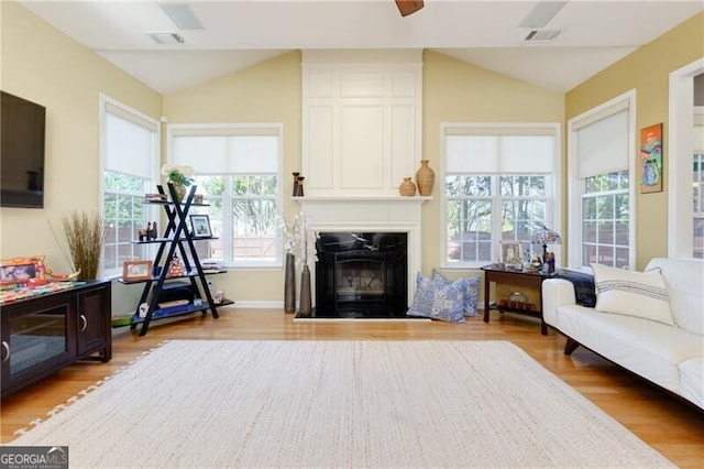 interior space featuring lofted ceiling, a large fireplace, light wood-type flooring, and visible vents