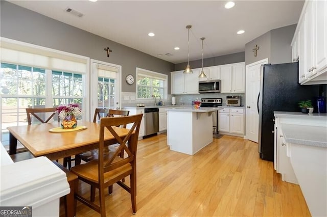 kitchen with appliances with stainless steel finishes, a center island, light countertops, and white cabinetry