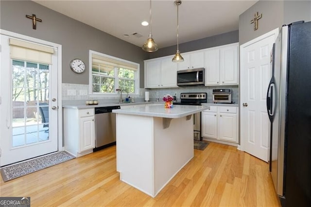 kitchen featuring white cabinetry, a kitchen island, appliances with stainless steel finishes, and light countertops