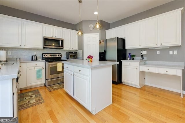 kitchen with stainless steel appliances, light countertops, hanging light fixtures, white cabinets, and a kitchen island