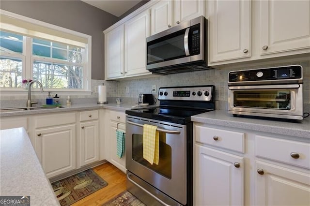 kitchen featuring stainless steel appliances, light countertops, white cabinets, and a sink