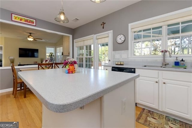 kitchen featuring hanging light fixtures, white cabinets, a sink, and light countertops