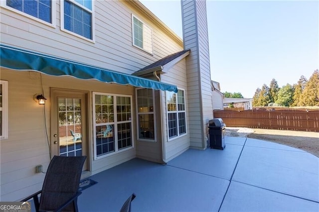 view of patio featuring fence and a grill