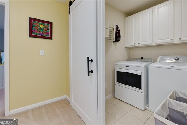 laundry area featuring cabinet space, a barn door, baseboards, independent washer and dryer, and light tile patterned flooring