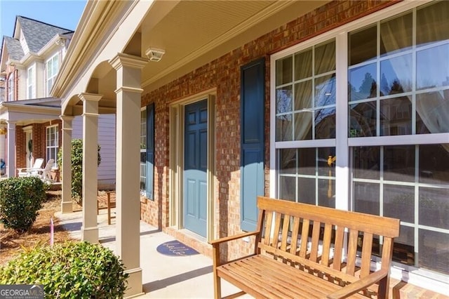 doorway to property with a porch and brick siding