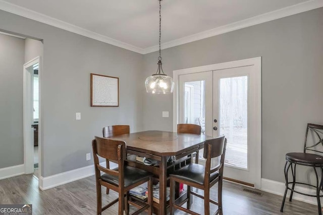 dining space featuring ornamental molding, french doors, visible vents, and wood finished floors