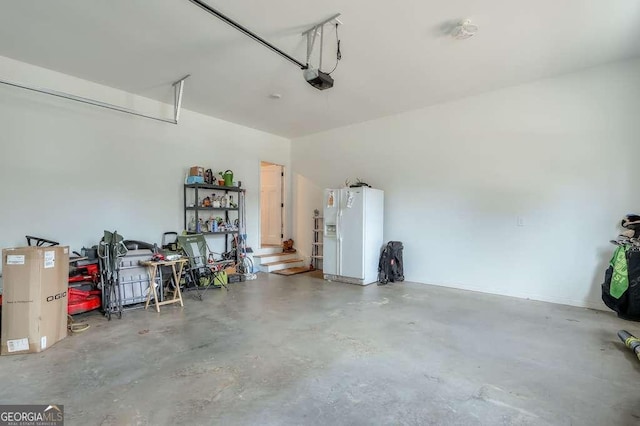 garage with a garage door opener and white refrigerator with ice dispenser