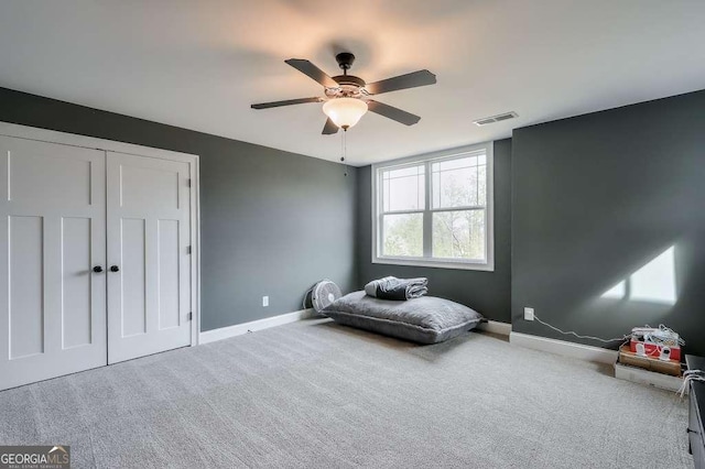 carpeted bedroom featuring a ceiling fan, a closet, visible vents, and baseboards