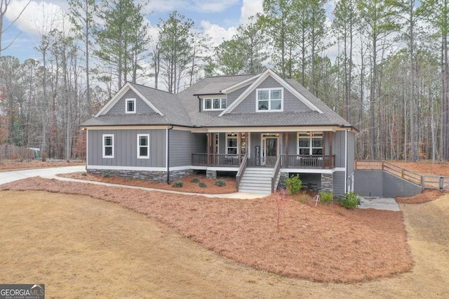 view of front of home with board and batten siding, covered porch, roof with shingles, and fence