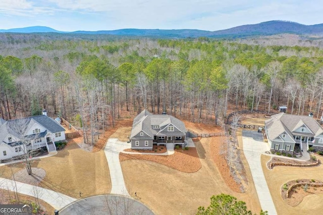 birds eye view of property featuring a wooded view and a mountain view