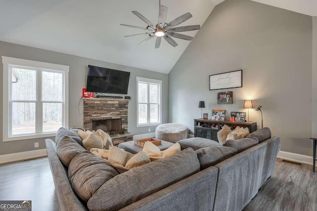 living room with high vaulted ceiling, a fireplace, wood finished floors, and baseboards