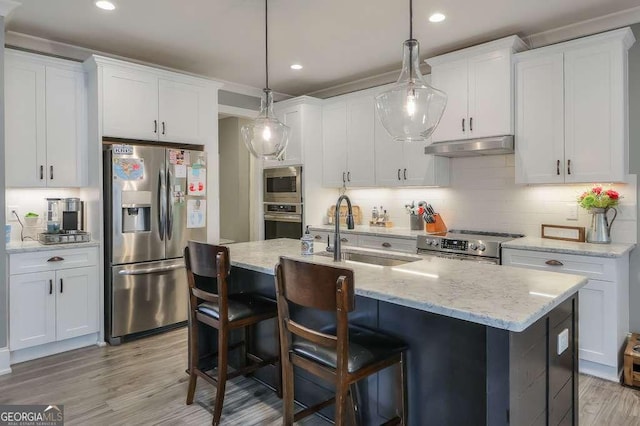 kitchen with white cabinets, decorative backsplash, stainless steel appliances, under cabinet range hood, and a sink