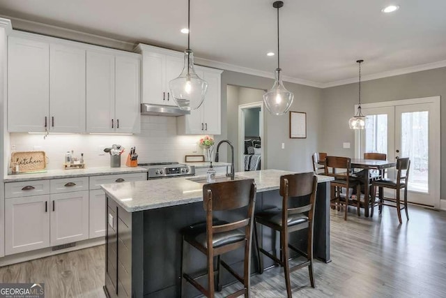 kitchen featuring a sink, white cabinets, stainless steel range oven, decorative backsplash, and crown molding