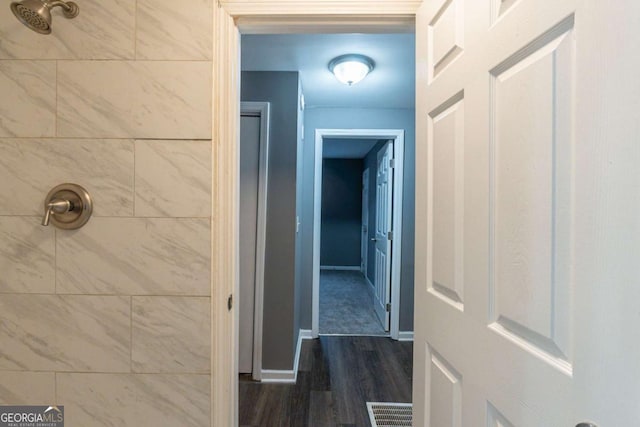 bathroom featuring baseboards, visible vents, a tile shower, and wood finished floors