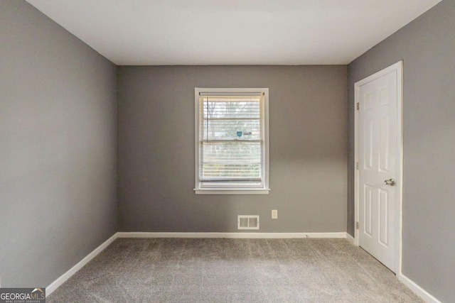 empty room with baseboards, visible vents, and light colored carpet