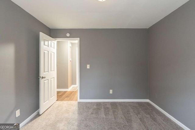 empty room with baseboards and light colored carpet