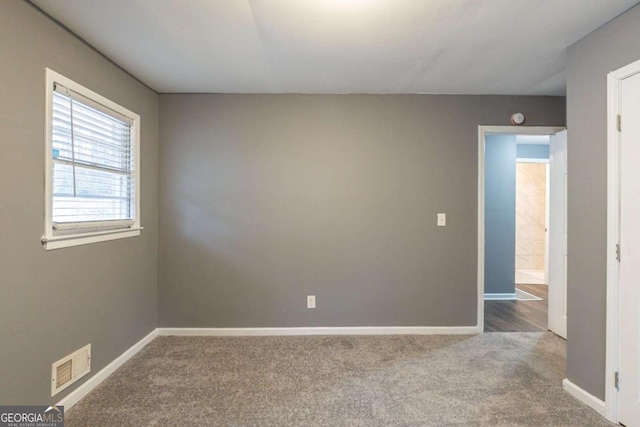 spare room featuring carpet floors, visible vents, and baseboards