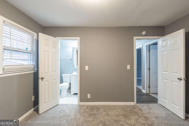 unfurnished bedroom featuring carpet flooring, connected bathroom, and baseboards