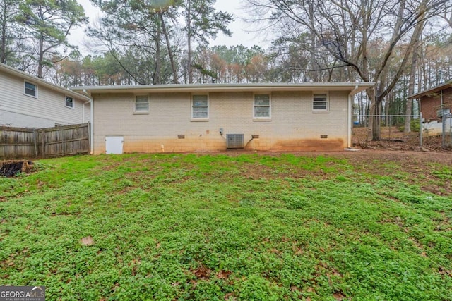 rear view of property with brick siding, a lawn, crawl space, cooling unit, and a fenced backyard