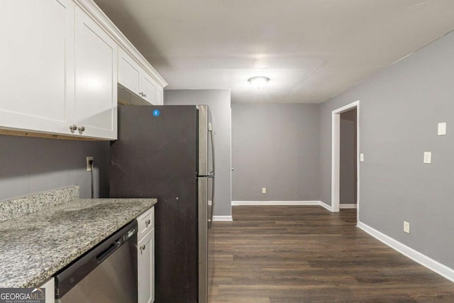 kitchen with stainless steel appliances, dark wood-style flooring, white cabinetry, baseboards, and light stone countertops