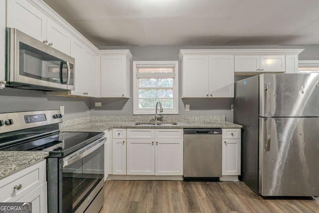 kitchen with appliances with stainless steel finishes, white cabinetry, and a sink