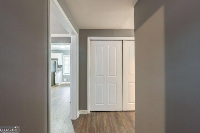 corridor featuring dark wood-type flooring, visible vents, and baseboards