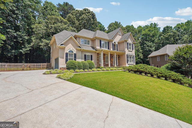 view of front of house featuring a garage, fence, concrete driveway, stucco siding, and a front lawn