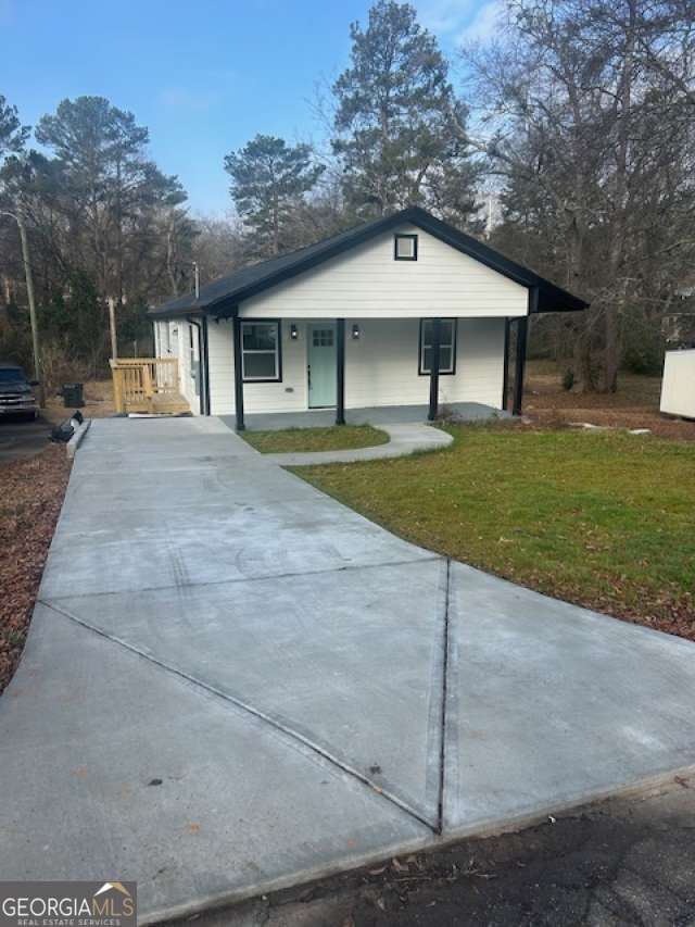 view of front of home featuring covered porch, a front lawn, and concrete driveway