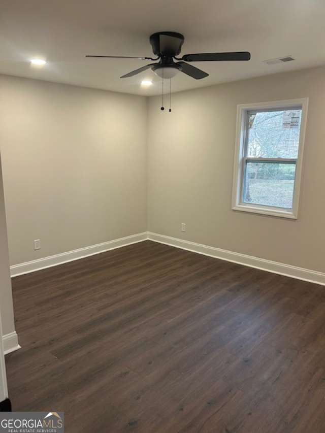 empty room with dark wood-style floors, recessed lighting, visible vents, ceiling fan, and baseboards