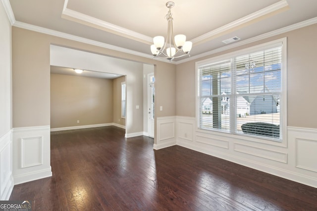 spare room featuring dark wood-type flooring, a raised ceiling, visible vents, and plenty of natural light