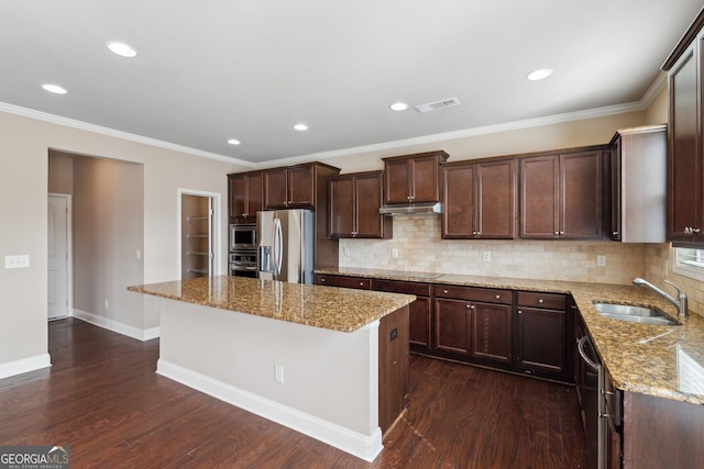 kitchen with light stone counters, a kitchen island, a sink, visible vents, and appliances with stainless steel finishes