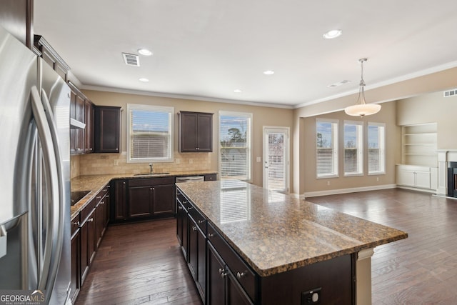 kitchen with a center island, decorative light fixtures, crown molding, visible vents, and stainless steel fridge with ice dispenser