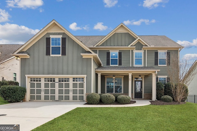 view of front facade with driveway, roof with shingles, an attached garage, a front lawn, and board and batten siding