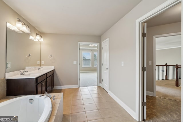 bathroom with double vanity, baseboards, tile patterned floors, a garden tub, and a sink