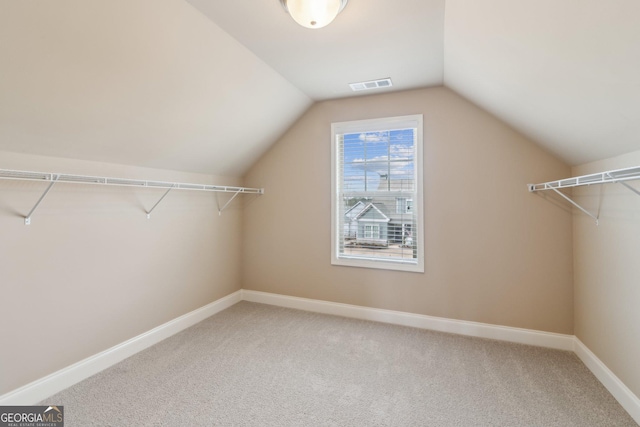 spacious closet with carpet floors, visible vents, and lofted ceiling