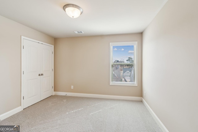 unfurnished bedroom featuring a closet, light colored carpet, visible vents, and baseboards