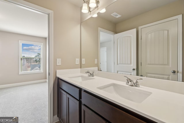 bathroom with double vanity, a sink, visible vents, and baseboards