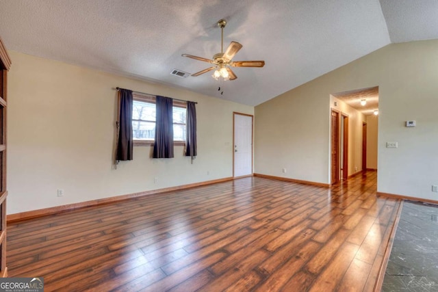 spare room with visible vents, dark wood-type flooring, vaulted ceiling, a textured ceiling, and ceiling fan