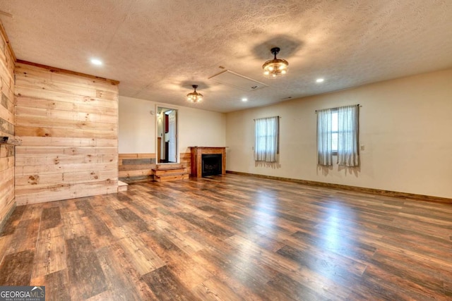 unfurnished living room with dark wood-style floors, a textured ceiling, a fireplace, and baseboards