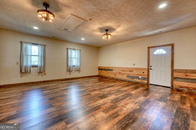 interior space with a textured ceiling, baseboards, dark wood-type flooring, and recessed lighting