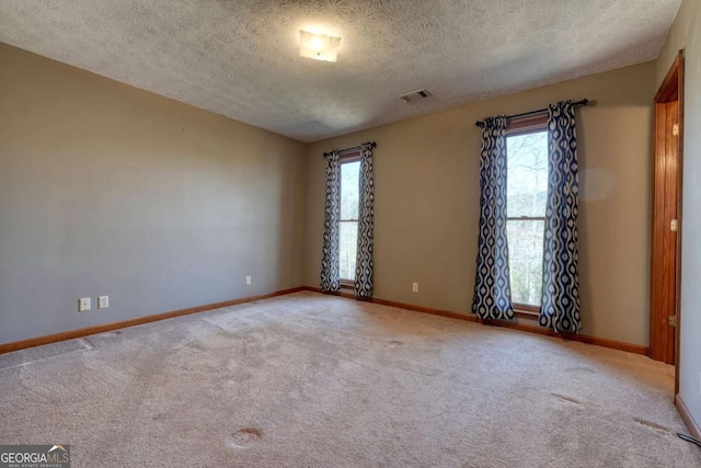 empty room featuring a healthy amount of sunlight, carpet, and visible vents