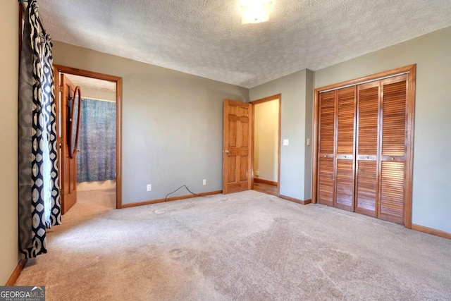 unfurnished bedroom with a textured ceiling, a closet, light colored carpet, and baseboards