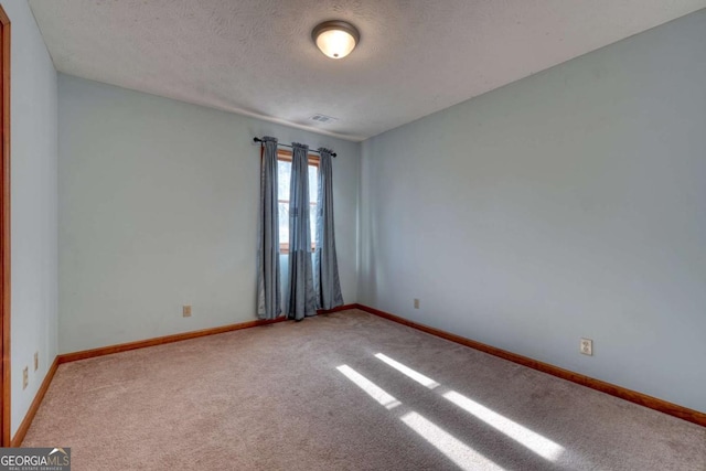 unfurnished room with light carpet, baseboards, and a textured ceiling