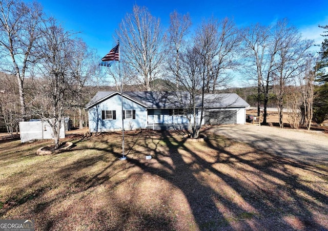 view of front of property featuring metal roof, driveway, and a front yard