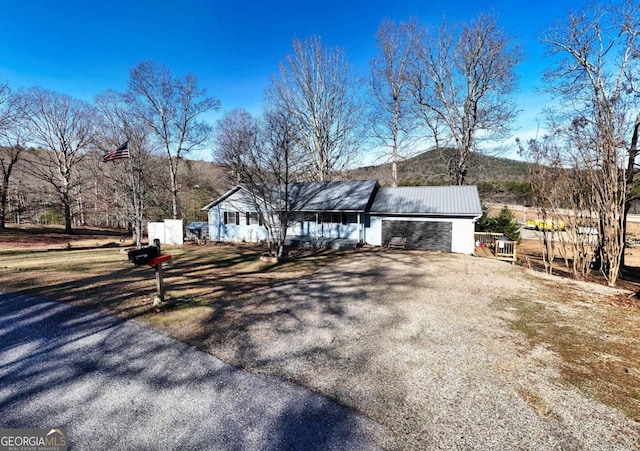 view of front of home featuring metal roof, driveway, an attached garage, and a mountain view