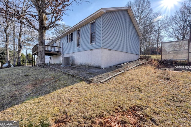 view of property exterior featuring central air condition unit, a lawn, and a wooden deck