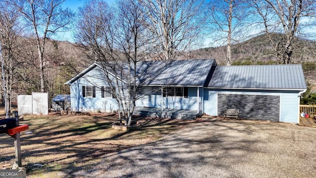 single story home with a garage, metal roof, a mountain view, and aphalt driveway