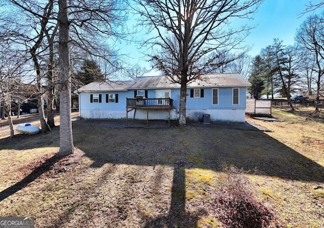 view of front of property with a front yard, metal roof, driveway, and a wooden deck