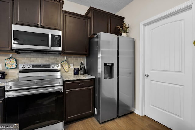 152 Summerhill Dr NE, Ludowici, GA 31316 - kitchen with stainless steel appliances, light wood finished floors, dark brown cabinetry, and tasteful backsplash